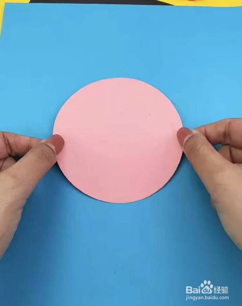 先取一张长方形的蓝色硬卡纸,再取一张浅粉色纸,剪出一个圆形,并把