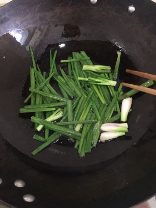 使用筷子翻炒葱花,让葱花沾满油,炸黑后捞出