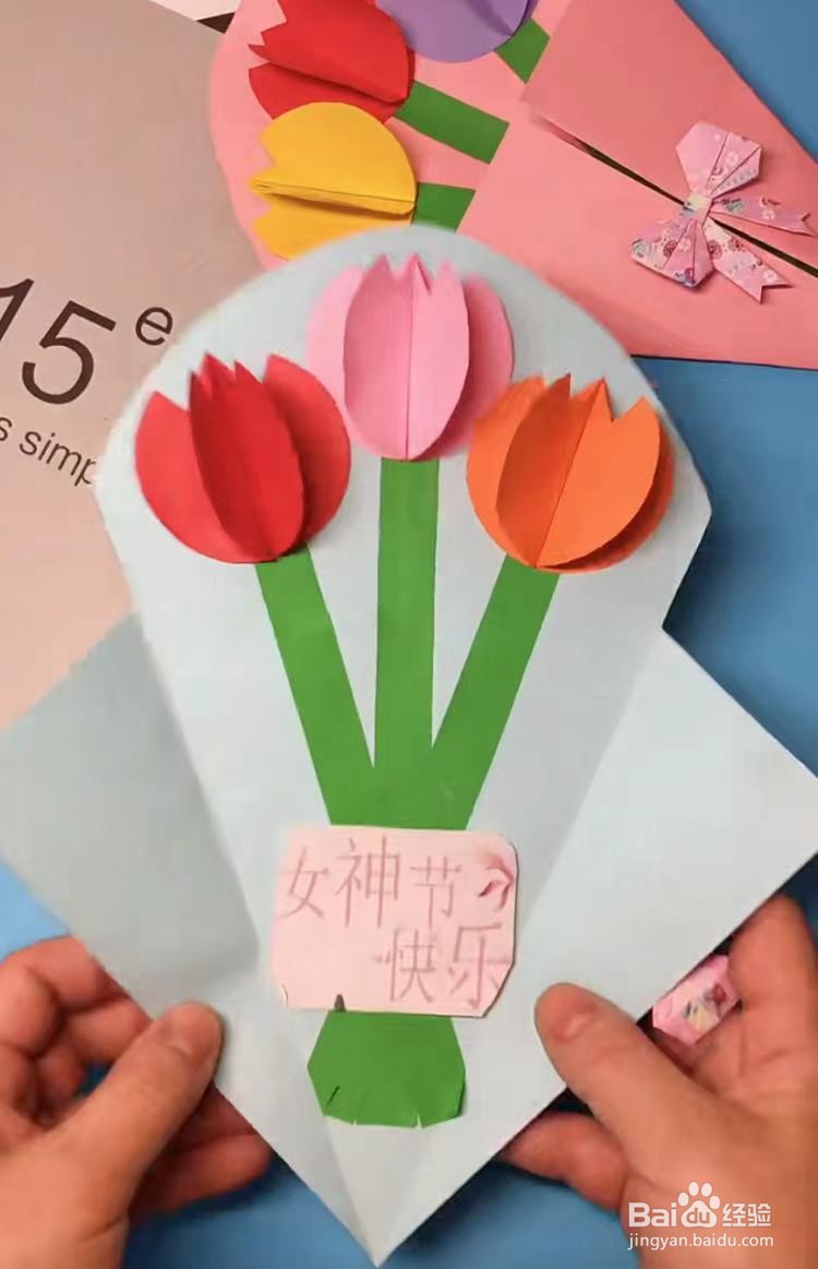 一张长方形粉色卡纸,粘贴在三条绿色长条的交叉处,并写上女神节快乐
