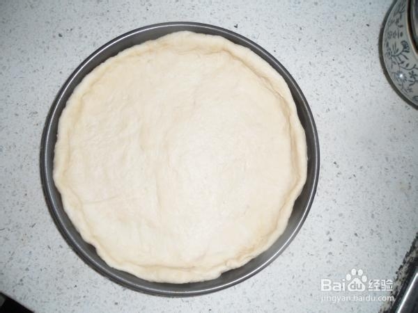 面团擀至圆形,放入披萨盘内,烤箱预热150℃,把披萨饼皮放进去一分钟