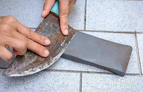 贴紧磨刀石 取出菜刀,刀刃紧贴着磨刀石表面,菜刀后部稍微翘起.