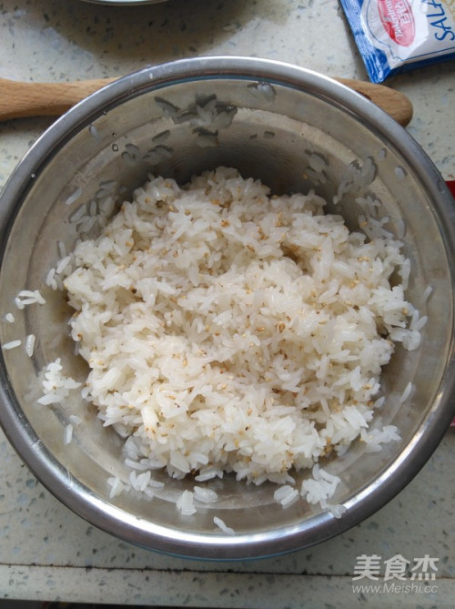 蒸好的米饭晾晾到温热,加入寿司醋,并搅拌均匀,然后加入熟白芝麻