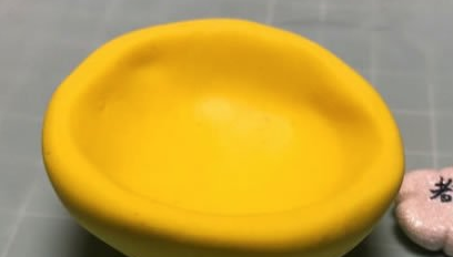 2 然后用白色粘土做一个椭圆形扁片,贴好作为脸部.